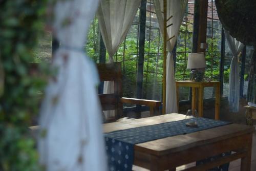 a room with a table and chairs and windows at H’nee House Ta Van in Sa Pa