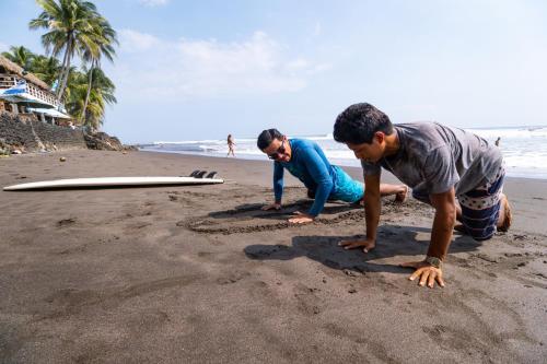 two men are playing on the beach with their surfboards at Olas Permanentes El Zonte in El Zonte