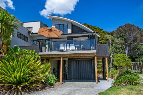 a house with a balcony and an umbrella at Harnifin - Langs Beach Holiday Home in Langs Beach