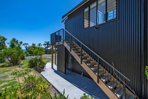 a black house with a staircase leading up to it at Harnifin - Langs Beach Holiday Home in Langs Beach