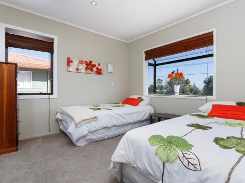 two beds in a room with two windows at At The Bay - Mt Maunganui Holiday Home in Matapihi