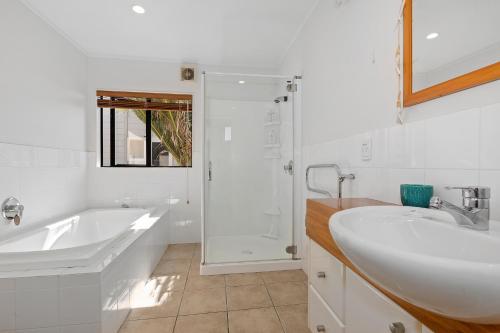 a white bathroom with a tub and a sink at Marina Views - Tutukaka Holiday Home in Tutukaka