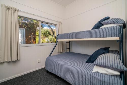 1 dormitorio con litera y ventana en Rangimarie on Kenwood- Matarangi Holiday Home, en Matarangi