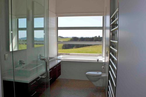 a bathroom with a sink and a toilet and a window at The Perfect Degree - Sandy Bay Holiday Home in Matapouri