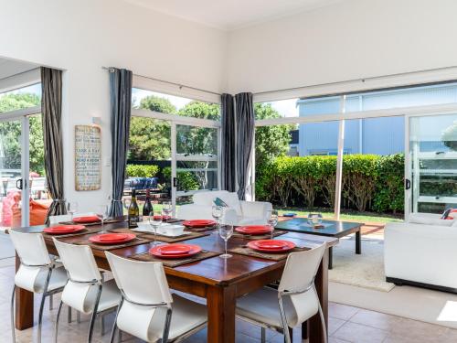 a dining room with a wooden table and white chairs at Magnifique - Mangawhai Holiday Home in Mangawhai
