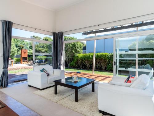 a living room with two white couches and a coffee table at Magnifique - Mangawhai Holiday Home in Mangawhai