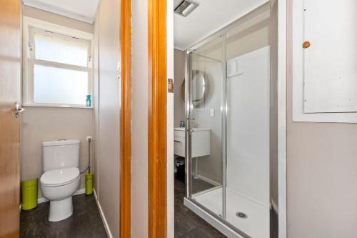 a bathroom with a toilet and a glass shower at Kulukulu - Ruakaka Holiday Home in Ruakaka