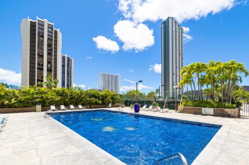 a swimming pool in a city with tall buildings at Newly Renovated 2 Bedroom Condo, 1 Block to Waikiki Beach, Free Parking in Honolulu