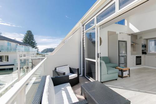 a balcony of a house with chairs and windows at Seaside Marine - Mt Maunganui Holiday Home in Mount Maunganui