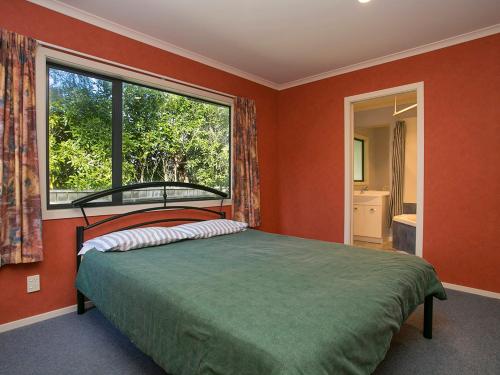 a bedroom with a bed and a large window at Laid Back on Lakewood - Taupo Holiday Home in Taupo