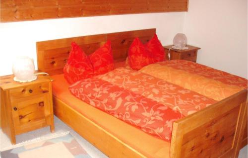 Schlafzimmer mit einem Holzbett mit roten Kissen in der Unterkunft Awesome Apartment In Nesselwang With Kitchenette in Nesselwang