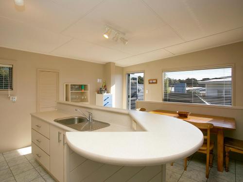 uma grande cozinha branca com um lavatório e uma mesa em Perfect Position - Motuoapa Holiday Home em Turangi