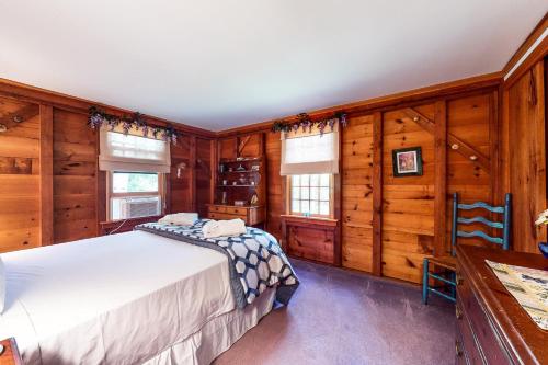 a bedroom with a bed and wooden walls at Pretty on Prada in Edgartown