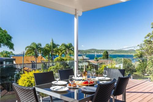 a dining table on a deck with a view of the water at Blue Waters 7 Cook St - Dog Friendly and Water Views in Salamander Bay