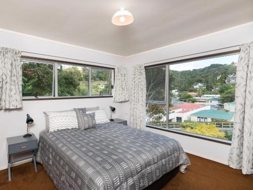 Schlafzimmer mit einem Bett und großen Fenstern in der Unterkunft Central Spacious Family House - Paihia House in Paihia