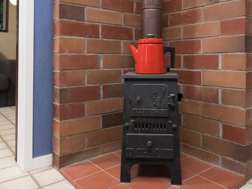 a black stove with a red pot on top at Central Spacious Family House - Paihia House in Paihia