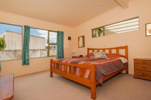 a bedroom with a bed and two windows at Surf Beach Views - Whangamata Holiday Home in Whangamata