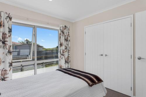 a bedroom with a bed and a large window at Beach Retreat - Ohope Holiday Home in Ohope Beach