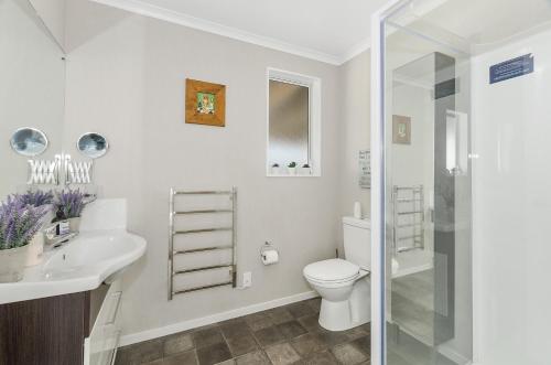 a white bathroom with a toilet and a sink at Little Pearl of Vista Verano - Mangawhai Home in Mangawhai