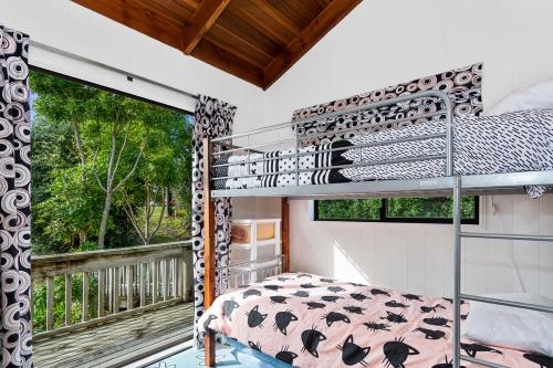 a bedroom with a bunk bed and a balcony at Riverview Retreat - Cooks Beach Holiday Home in Cooks Beach
