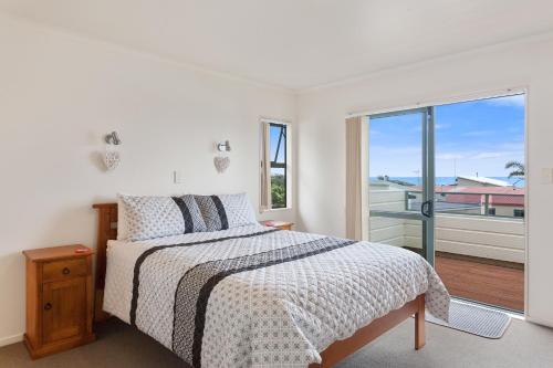 a white bedroom with a bed and a large window at White Island Views - Ohope Holiday Home in Ohope Beach