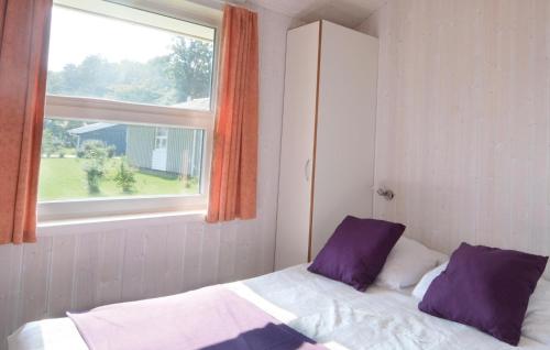 Un dormitorio con una cama con almohadas moradas y una ventana en Strandblick 14 en Schönhagen