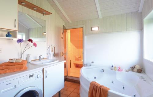a bathroom with a tub and a sink and a washing machine at Strandblick 14 in Schönhagen