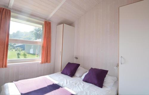 ein Schlafzimmer mit einem Bett mit lila Kissen und einem Fenster in der Unterkunft Strandblick 4 in Schönhagen