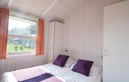 ein Schlafzimmer mit einem Bett mit lila Kissen und einem Fenster in der Unterkunft Strandblick 10 in Schönhagen