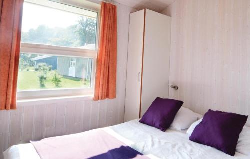 ein Schlafzimmer mit einem Bett mit lila Kissen und einem Fenster in der Unterkunft Strandpark 22 in Schönhagen