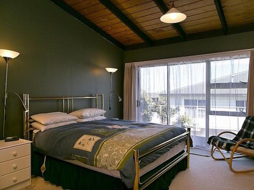 a bedroom with a bed and a large window at Golders Heights - Taupo Holiday Home in Taupo