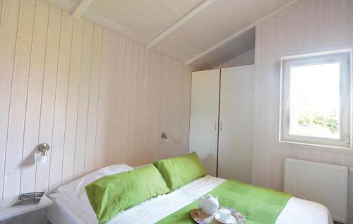 Schlafzimmer mit einem Bett mit grüner Bettwäsche und einem Fenster in der Unterkunft Strandblick 4 - Dorf 1 in Travemünde