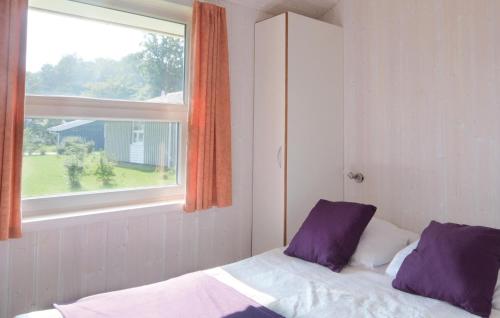 Bett mit lila Kissen in einem Zimmer mit Fenster in der Unterkunft Strandblick 14 - Dorf 1 in Travemünde