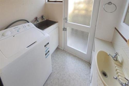 a small bathroom with a sink and a washing machine at Joes Place - Cooks Beach Holiday Home in Cooks Beach