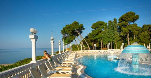 
a beach scene with a couple of people in the water at Island Hotel Katarina in Rovinj
