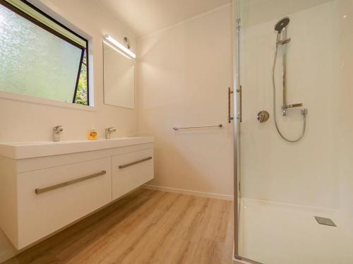 y baño con ducha, lavabo y espejo. en The Bach Retreat - Hahei Holiday House, en Hahei