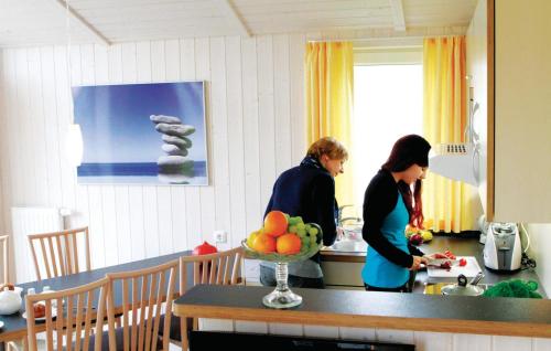 two women standing in a kitchen with a bowl of fruit at Friedrichskoog-Deichblick 7 in Friedrichskoog