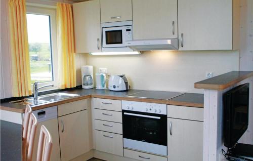 a kitchen with white cabinets and a sink and a microwave at Friedrichskoog-Deichblick 9 in Friedrichskoog