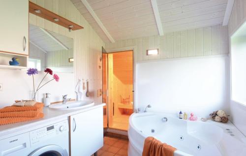 ein Badezimmer mit einer Badewanne, einem Waschbecken und einer Waschmaschine in der Unterkunft Friedrichskoog-strandpark 14 in Friedrichskoog