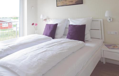 ein weißes Bett mit weißer Bettwäsche und lila Kissen in der Unterkunft Ferienhaus K�stenweg F in Dagebüll
