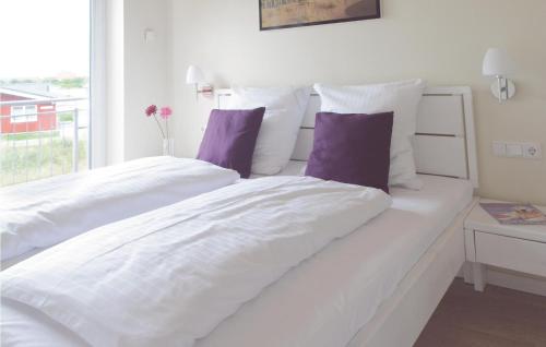 una cama blanca con sábanas blancas y almohadas moradas en 3 Bedroom Nice Home In Dagebüll, en Dagebüll