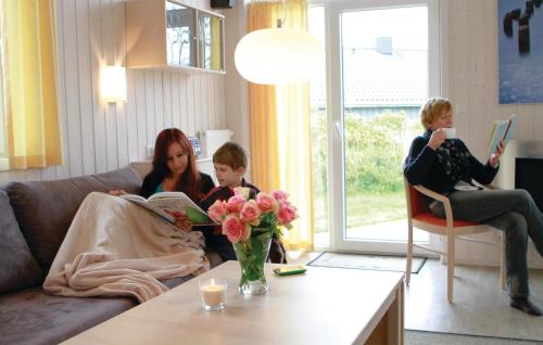 two women and a child reading a book in a living room at Friedrichskoog-Deichblick 5 in Friedrichskoog