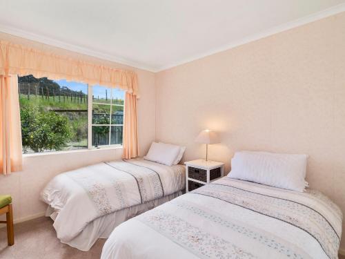 two beds in a room with a window at Laketop Retreat - Acacia Bay Holiday Home in Taupo