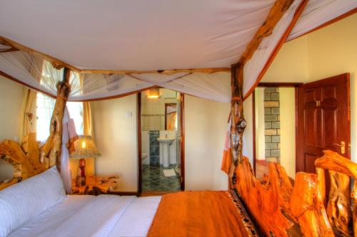 - une chambre avec un lit à baldaquin et une salle de bains dans l'établissement Naivasha Kongoni Lodge - Lakefront Getaway, à Naivasha