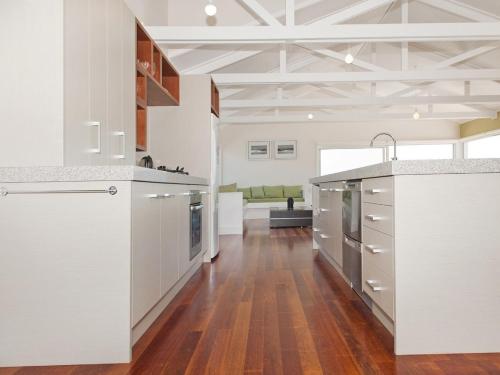 cocina con armarios blancos y suelo de madera en Views on Matarangi - Matarangi Holiday Home, en Matarangi