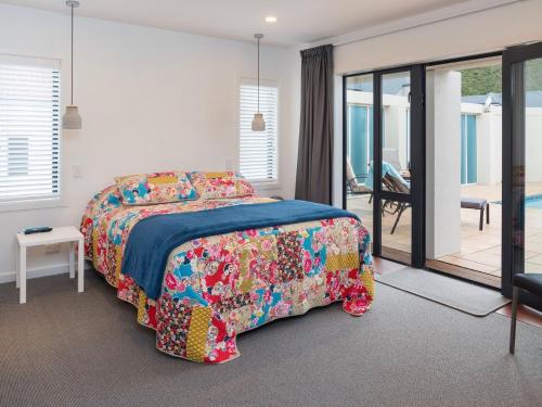 a bedroom with a bed with a colorful bedspread at Poolside Retreat - Picton Holiday House Waikawa in Picton