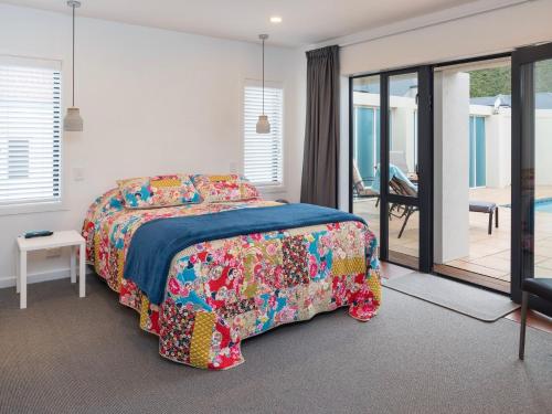 ein Schlafzimmer mit einem Bett mit einer farbenfrohen Tagesdecke in der Unterkunft Poolside Retreat - Picton Holiday House Waikawa in Picton