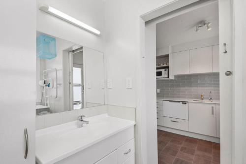 a white bathroom with a sink and a mirror at Central Stay - Taupo Flat in Taupo