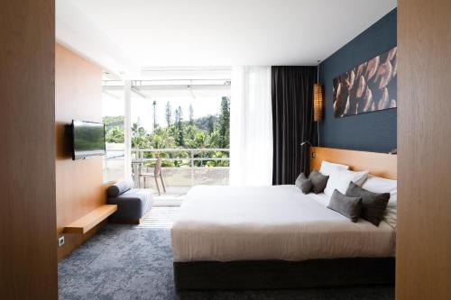 Habitación de hotel con cama y ventana grande en Chateau Royal Beach Resort & Spa, Noumea, en Noumea