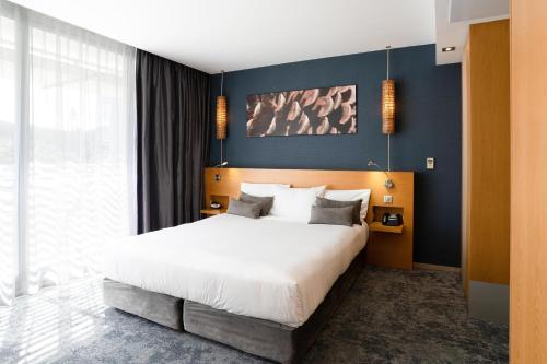 a bedroom with a large bed and a blue wall at Chateau Royal Beach Resort & Spa, Noumea in Noumea